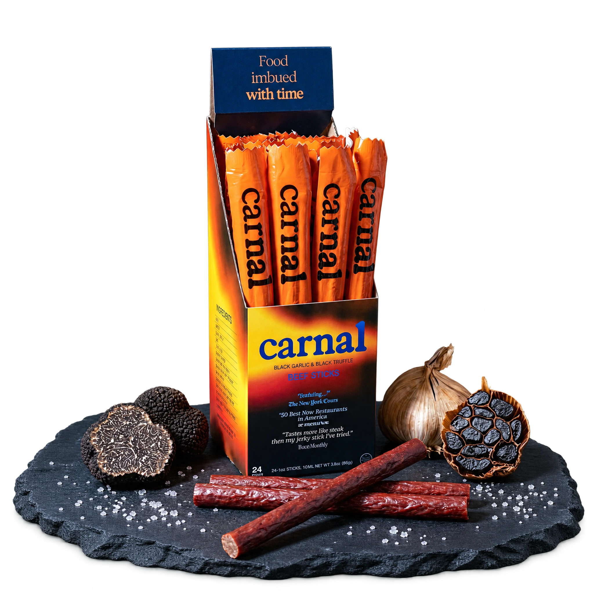 Carnal Black Truffle and Black Garlic Beef Sticks display box with beef sticks, truffles, black garlic, and salt on slate